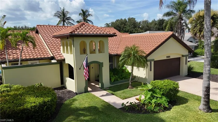 Mediterranean-inspired two-story residence featuring a terracotta tile roof, cream stucco exterior, and arched entryway