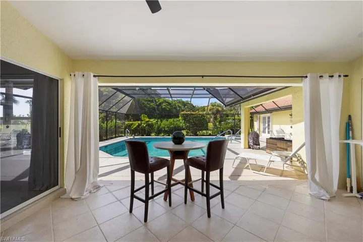 Covered patio with neutral tile flooring, ceiling fan, and sliding glass door