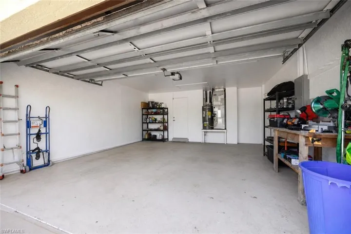 Spacious garage with exposed metal door track system, white painted walls, and a visible water heater installation
