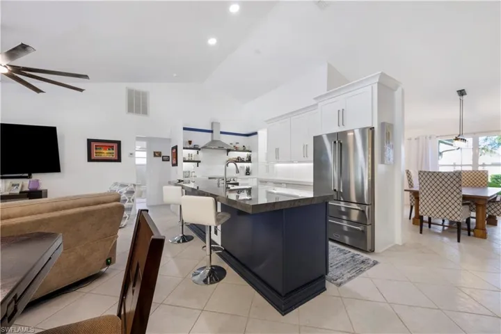 Open-concept living space featuring vaulted ceilings, a kitchen island with seating, stainless steel appliances, and white cabinetry