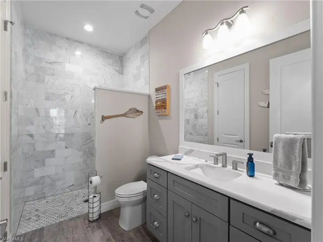 Bathroom featuring walk in shower, vanity, and light wood finished floors