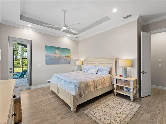 Bedroom with recessed lighting, a raised ceiling, access to exterior, light wood-type flooring, and crown molding