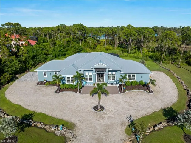 View of front of property with a metal roof and curved driveway