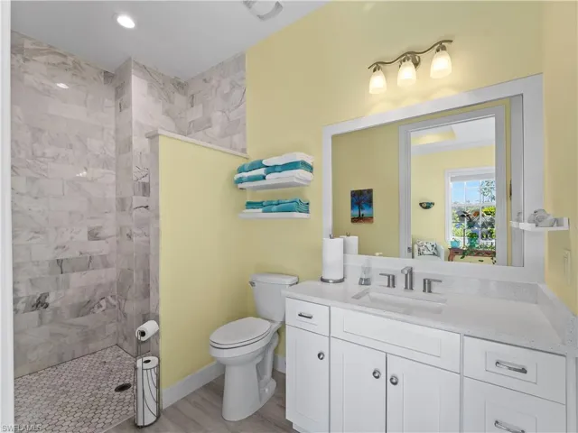 Bathroom with walk in shower, vanity, and light wood finished floors