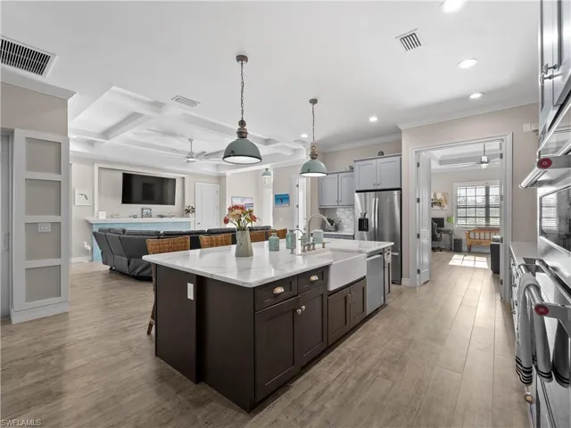 Kitchen with ceiling fan, pendant lighting, a kitchen breakfast bar, coffered ceiling, and open floor plan
