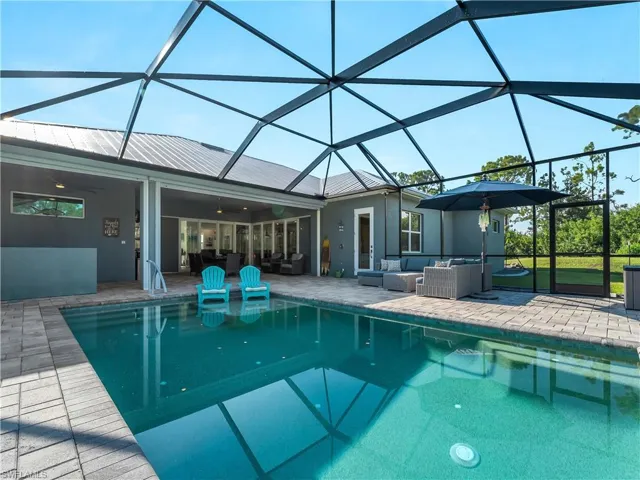 Outdoor pool featuring glass enclosure, a sunroom, a patio area, and outdoor lounge area