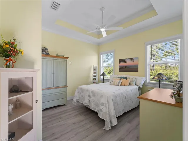 Bedroom with a tray ceiling, crown molding, wood finished floors, and ceiling fan