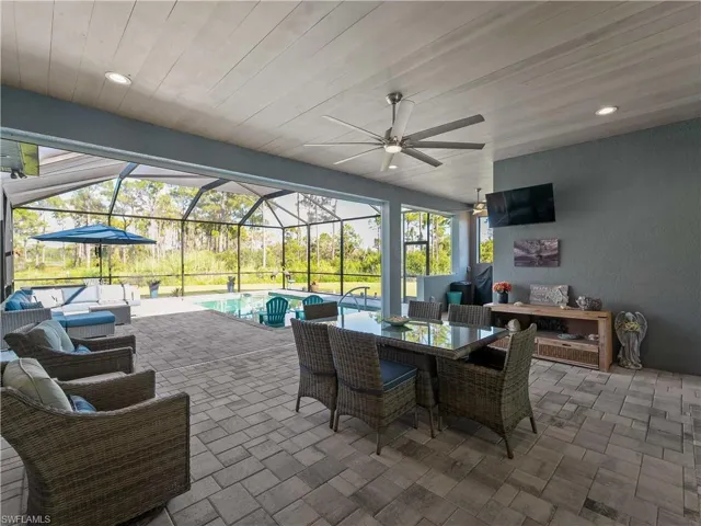 View of patio / terrace featuring a sunroom, glass enclosure, an outdoor pool, an outdoor living space, and ceiling fan