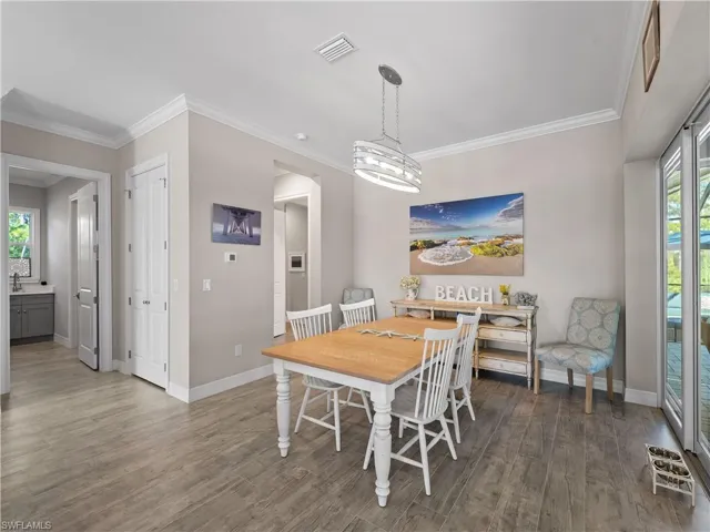 Dining space with crown molding, wood finished floors, and a chandelier