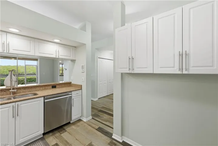Kitchen with white cabinetry, dishwasher, granite countertops, light wood-type flooring
