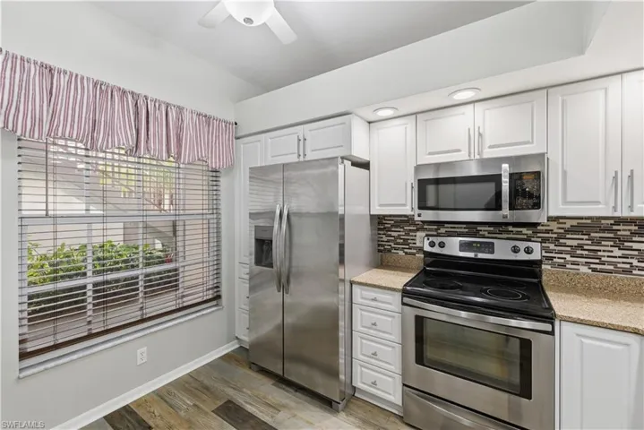Kitchen featuring stainless steel appliances, white cabinetry, a ceiling fan, and granite counters