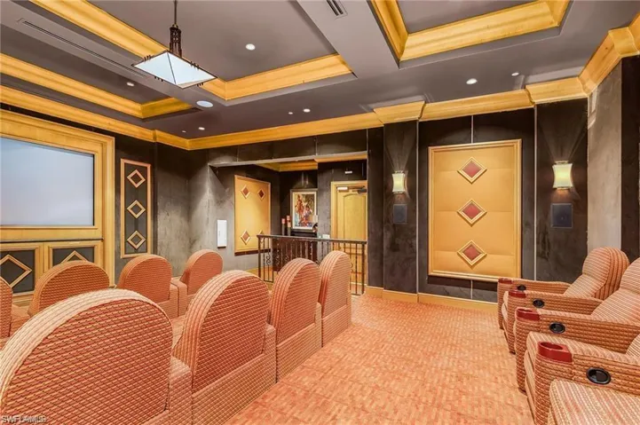 Home theater featuring visible vents, a raised ceiling, and ornamental molding
