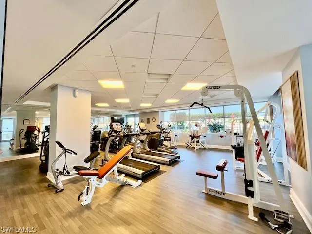 Workout area with wood finished floors, baseboards, and a drop ceiling