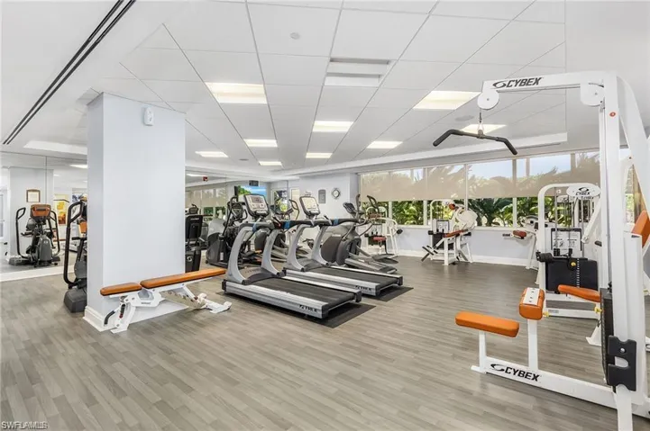 Gym featuring baseboards, a paneled ceiling, and wood finished floors