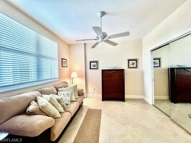 Living area featuring light tile patterned floors, a ceiling fan, and baseboards