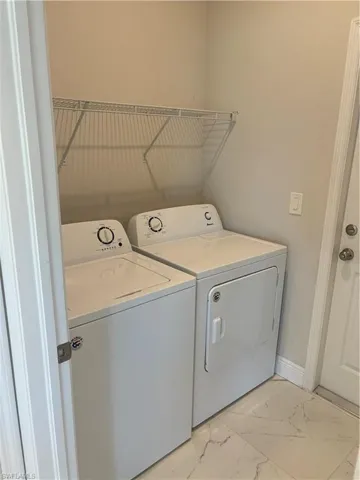 Clothes washing area featuring separate washer and dryer and light tile flooring