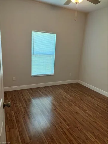 Unfurnished room featuring ceiling fan and dark hardwood / wood-style flooring
