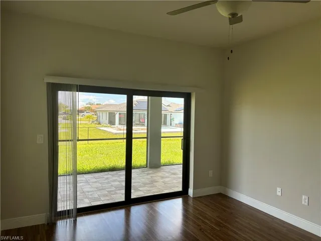 Empty room featuring ceiling fan and dark hardwood / wood-style flooring