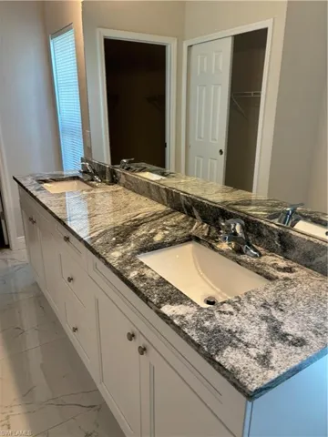 Bathroom with vanity with extensive cabinet space, tile flooring, and dual sinks