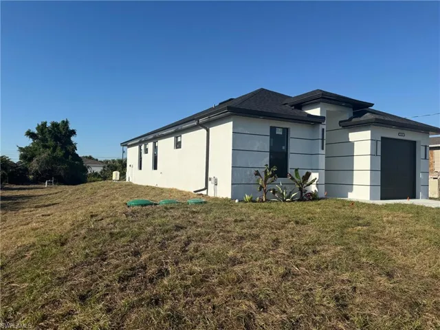 View of side of home featuring an attached garage, stucco siding, and a lawn