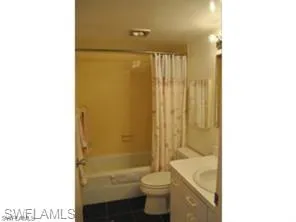 Bathroom with vanity, toilet, and shower / bath combo with shower curtain
