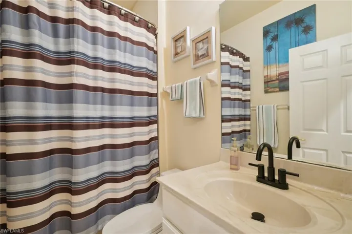Bathroom featuring a shower with curtain, toilet, and vanity