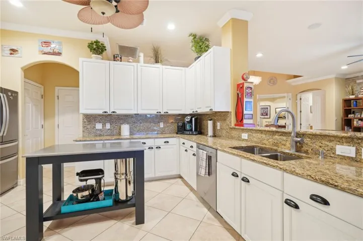 Kitchen with decorative backsplash, a sink, stainless steel appliances, and a ceiling fan