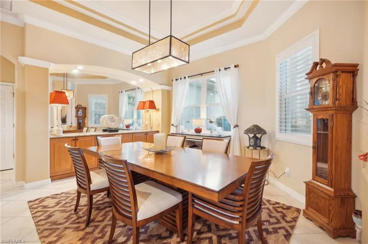 Dining area featuring a tray ceiling, light tile patterned flooring, and ornamental molding