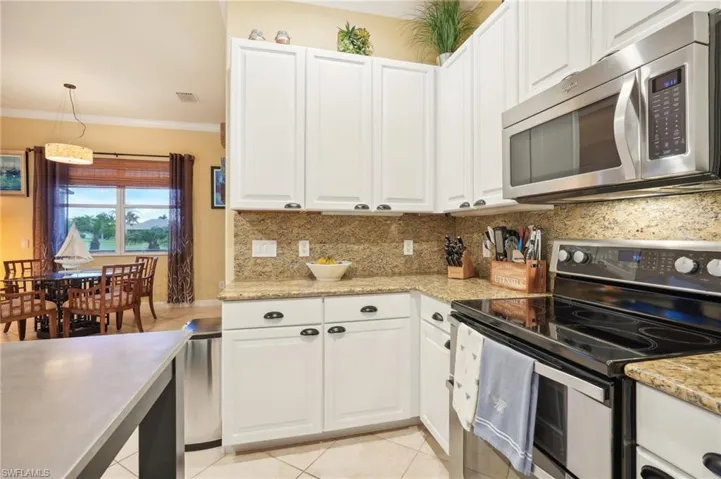 Kitchen featuring white cabinets, visible vents, ornamental molding, stainless steel appliances, and backsplash