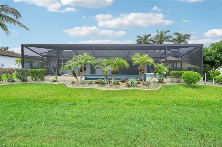 Rear view of property featuring a lanai, an outdoor pool, and a yard