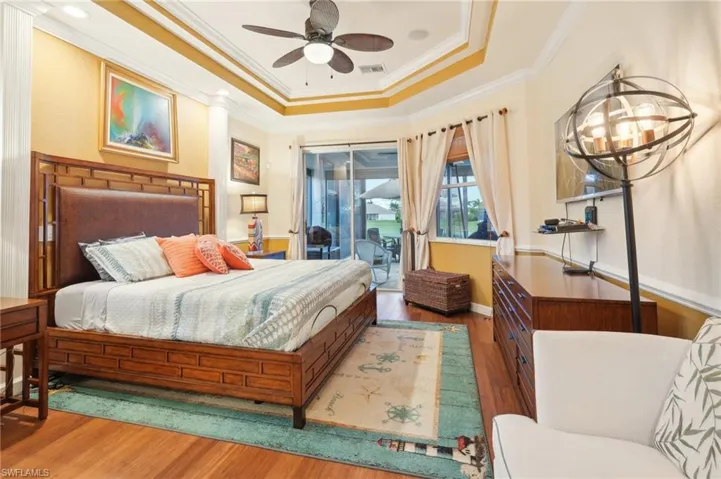 Bedroom featuring visible vents, ornamental molding, access to outside, wood finished floors, and a raised ceiling