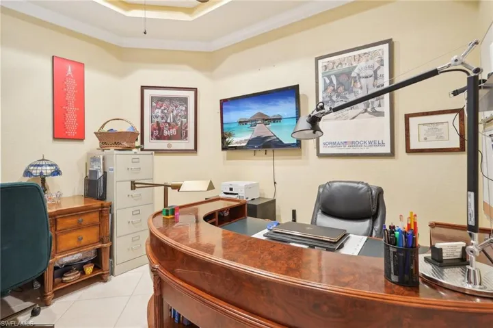Office featuring light tile patterned flooring and a tray ceiling