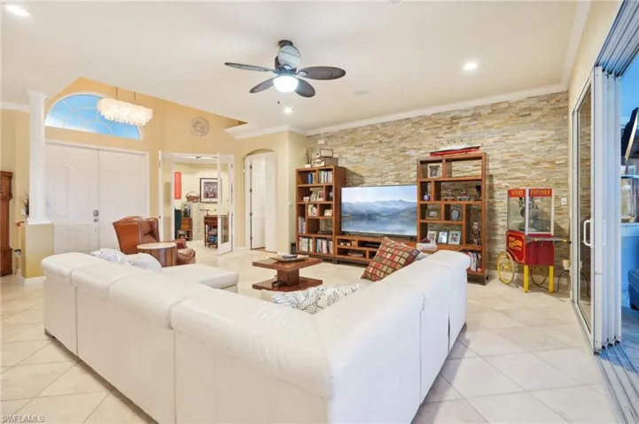 Living room featuring crown molding, recessed lighting, a ceiling fan, arched walkways, and light tile patterned floors