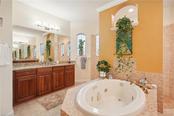 Bathroom featuring tile walls, a jetted tub, tile patterned floors, and vanity