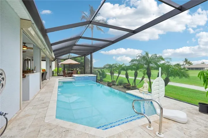 View of pool featuring a patio, an outdoor kitchen, a yard, and glass enclosure