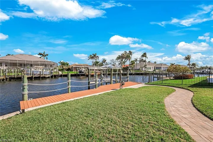 View of dock featuring a water view, a residential view, a lawn, and boat lift