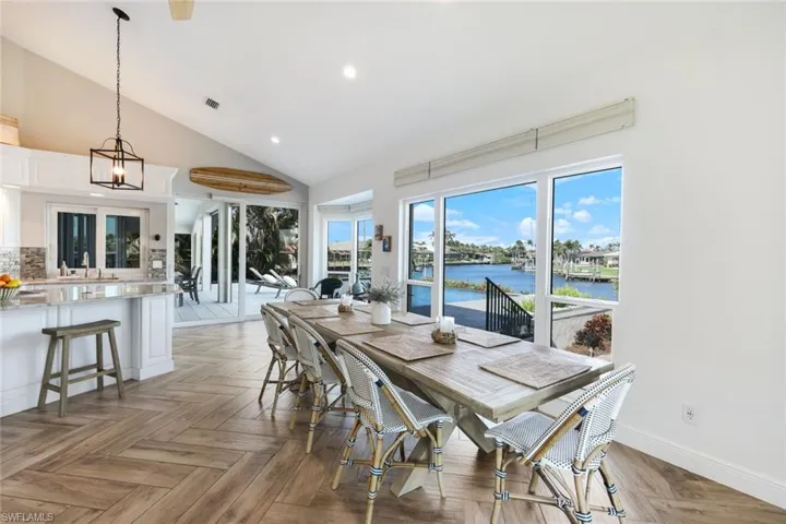 Dining area with high vaulted ceiling, visible vents, recessed lighting, a water view, and a notable chandelier