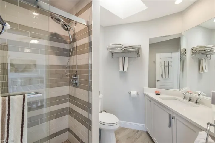Bathroom with a shower stall, a skylight, wood finished floors, and vanity