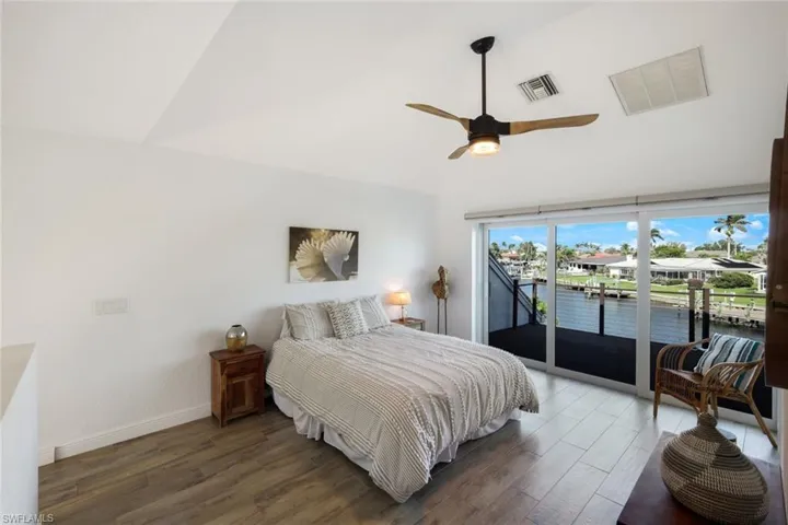 Bedroom featuring high vaulted ceiling, visible vents, access to exterior, and wood finished floors