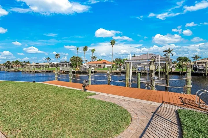 Dock area with a yard, a residential view, a water view, and boat lift