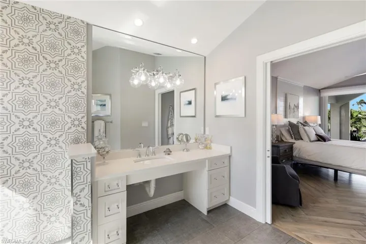 Ensuite bathroom with baseboards, recessed lighting, vanity, ensuite bath, and lofted ceiling