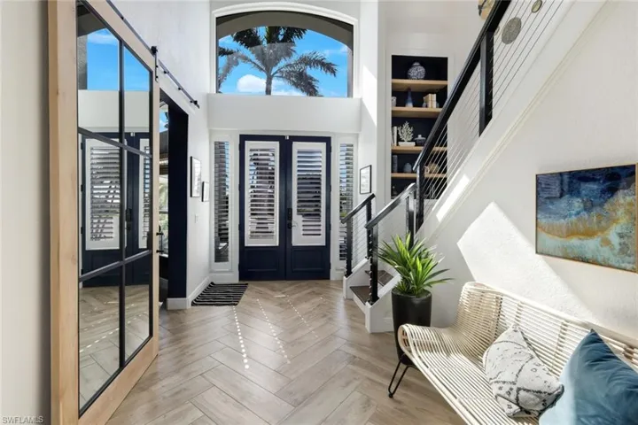 Foyer entrance with a barn door, a towering ceiling, and stairs