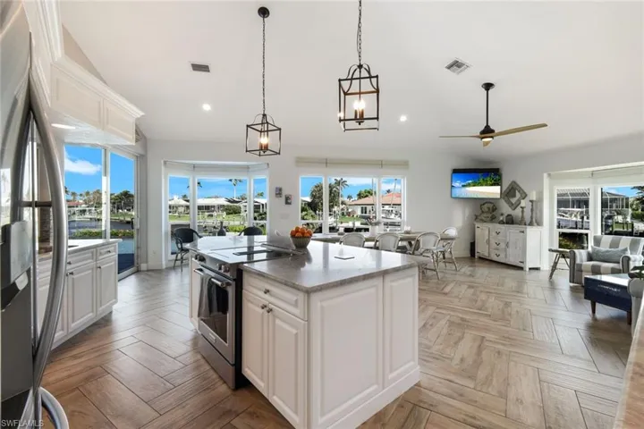 Kitchen with open floor plan, an island with sink, white cabinetry, recessed lighting, and stainless steel appliances