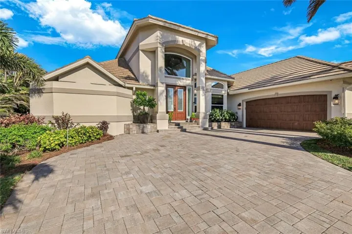 Mediterranean / spanish-style home featuring an attached garage, a tiled roof, stucco siding, and decorative driveway