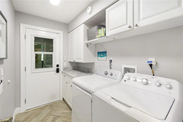 Clothes washing area featuring baseboards, washing machine and clothes dryer, and cabinet space