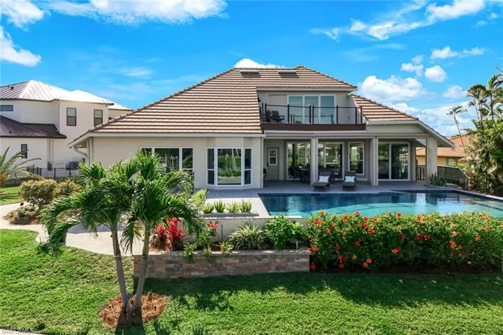 Rear view of property with a yard, stucco siding, fence, a tile roof, and a balcony