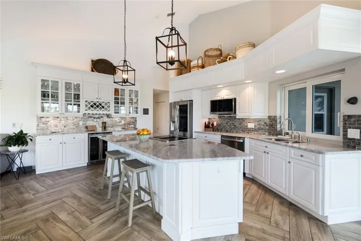 Kitchen featuring backsplash, appliances with stainless steel finishes, and beverage cooler