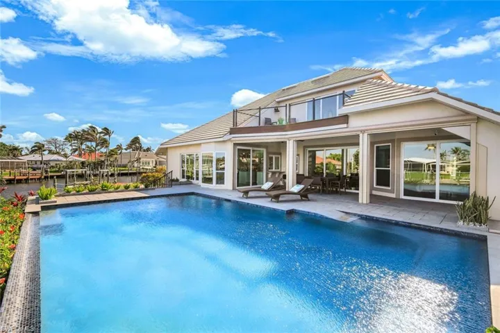 Rear view of property with a patio area, an outdoor pool, a tile roof, and stucco siding