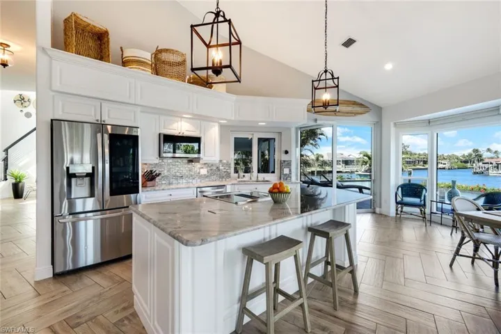 Kitchen with high vaulted ceiling, white cabinetry, visible vents, a kitchen island, and appliances with stainless steel finishes