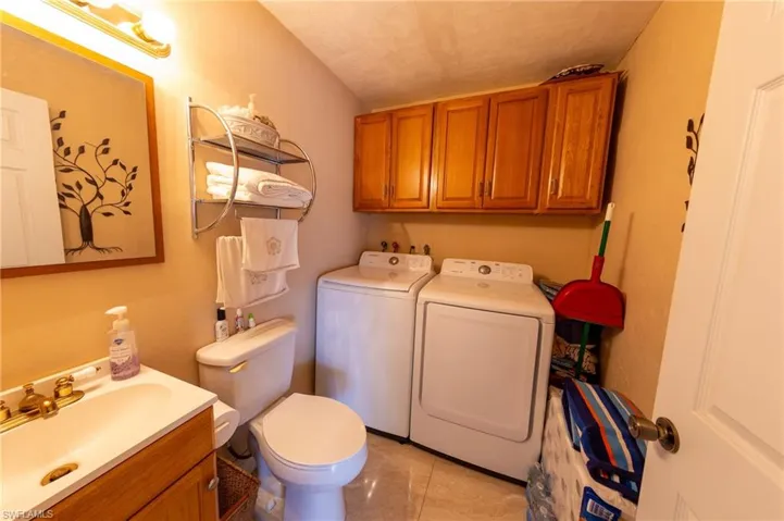 Half bathroom with vanity, washing machine and dryer, and light tile patterned floors